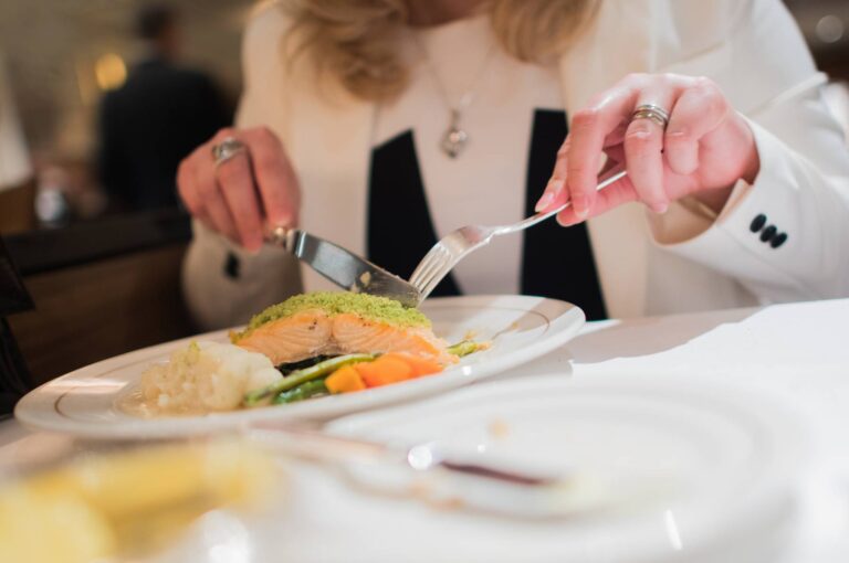 Elegant Restaurant Dinner. Grilled Salmon with Vegetables. Woman Eating Dinner.